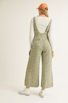 Person wearing a green floral jumpsuit on a white background
