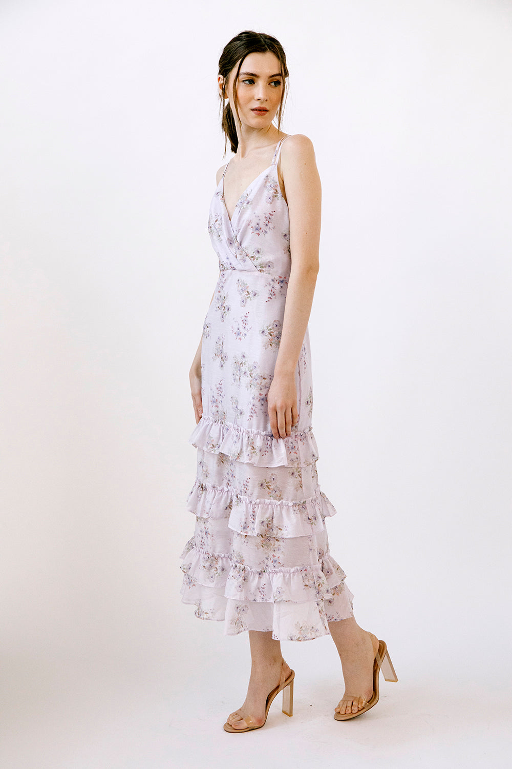 Side view of a woman wearing a lilac floral midi dress on a white background