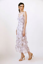 Side view of a woman wearing a lilac floral midi dress on a white background