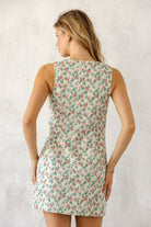 A woman viewed from behind wearing a cotton floral mini dress featuring a vintage rose garden print and an effortless shift silhouette made for warm-weather styling.