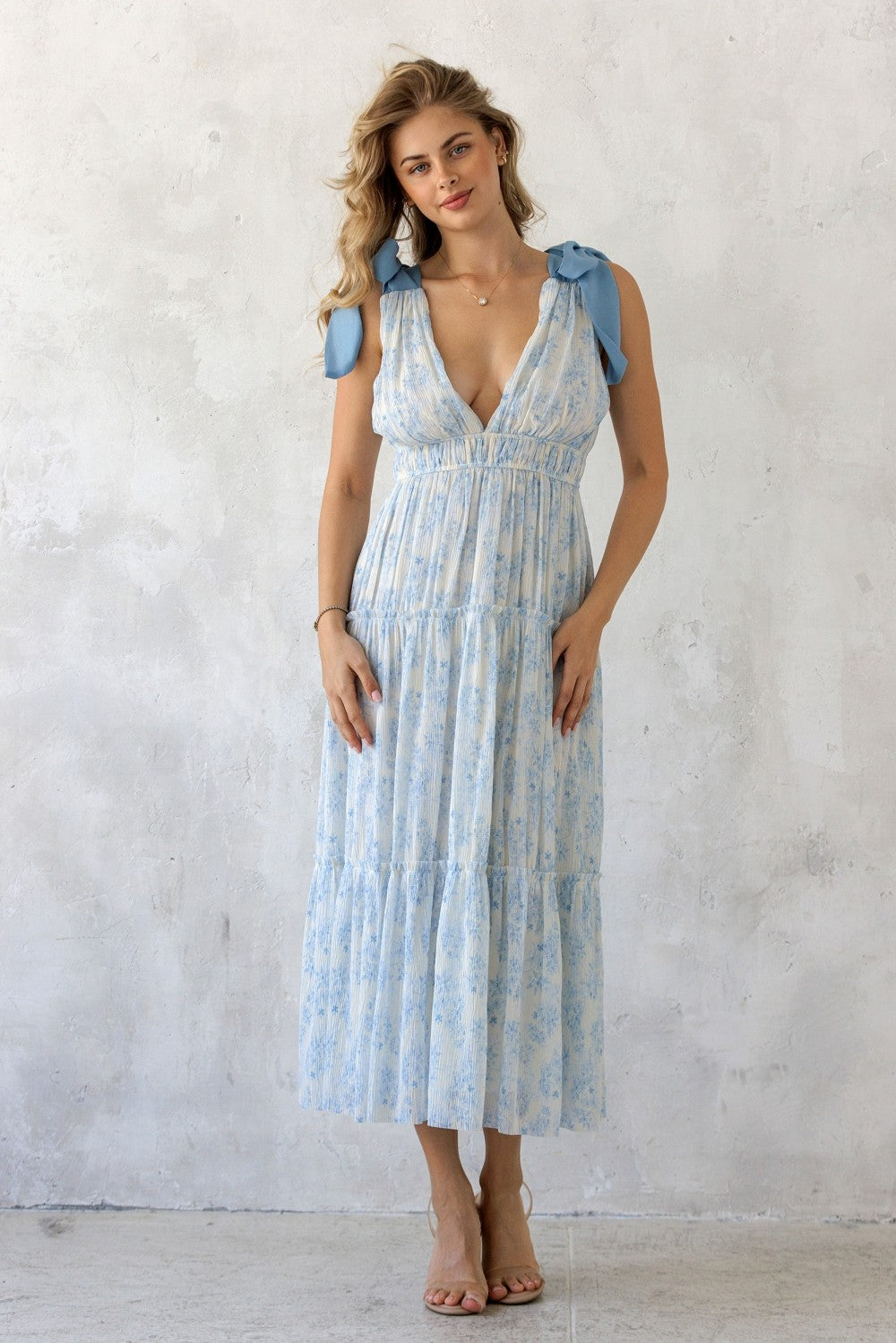 Woman wearing a light blue floral dress with ruffled sleeves against a white background