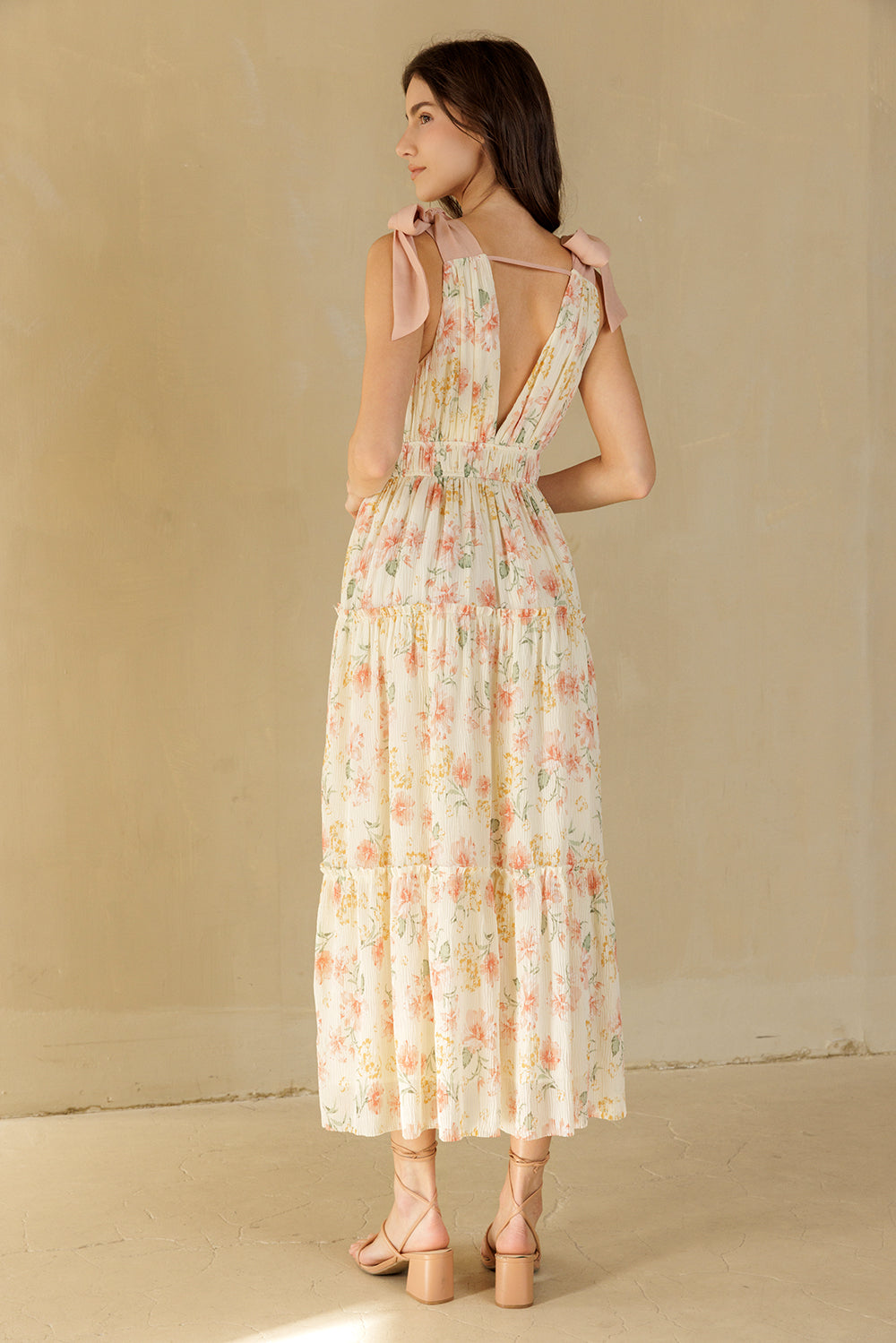 Woman wearing a cream floral dress against a beige background