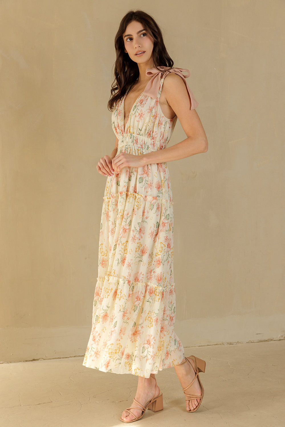 Woman wearing a cream floral dress against a beige background