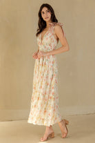 Woman wearing a cream floral dress against a beige background