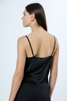 A woman viewed from behind wearing a black top with adjustable spaghetti strips.