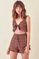 Woman wearing a leopard print cropped top and shorts on a beige background