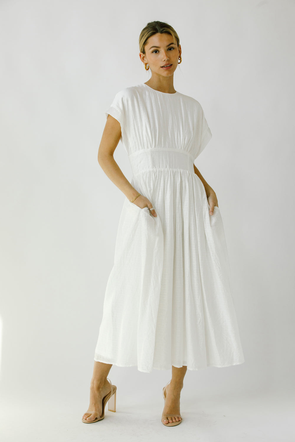 Woman wearing a white midi dress against a plain background