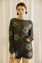 Woman wearing a dark gray knit outfit with floral patterns against a neutral background