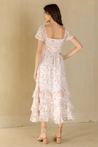 Woman wearing a white and pink floral dress against a beige background