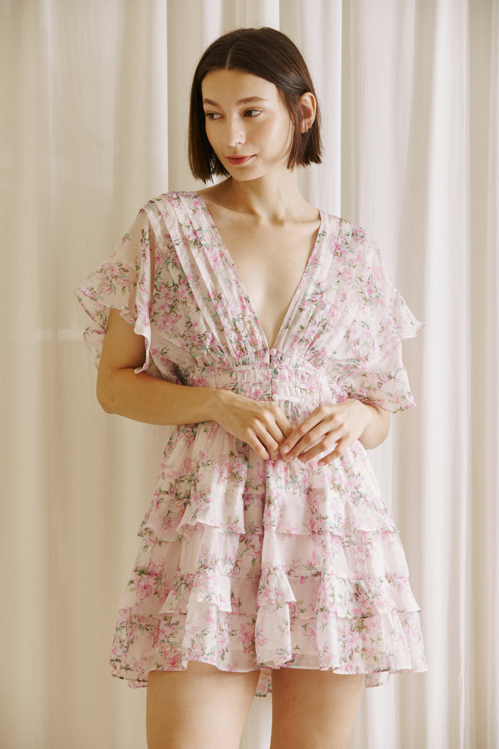 Woman wearing a pink floral dress against a neutral background