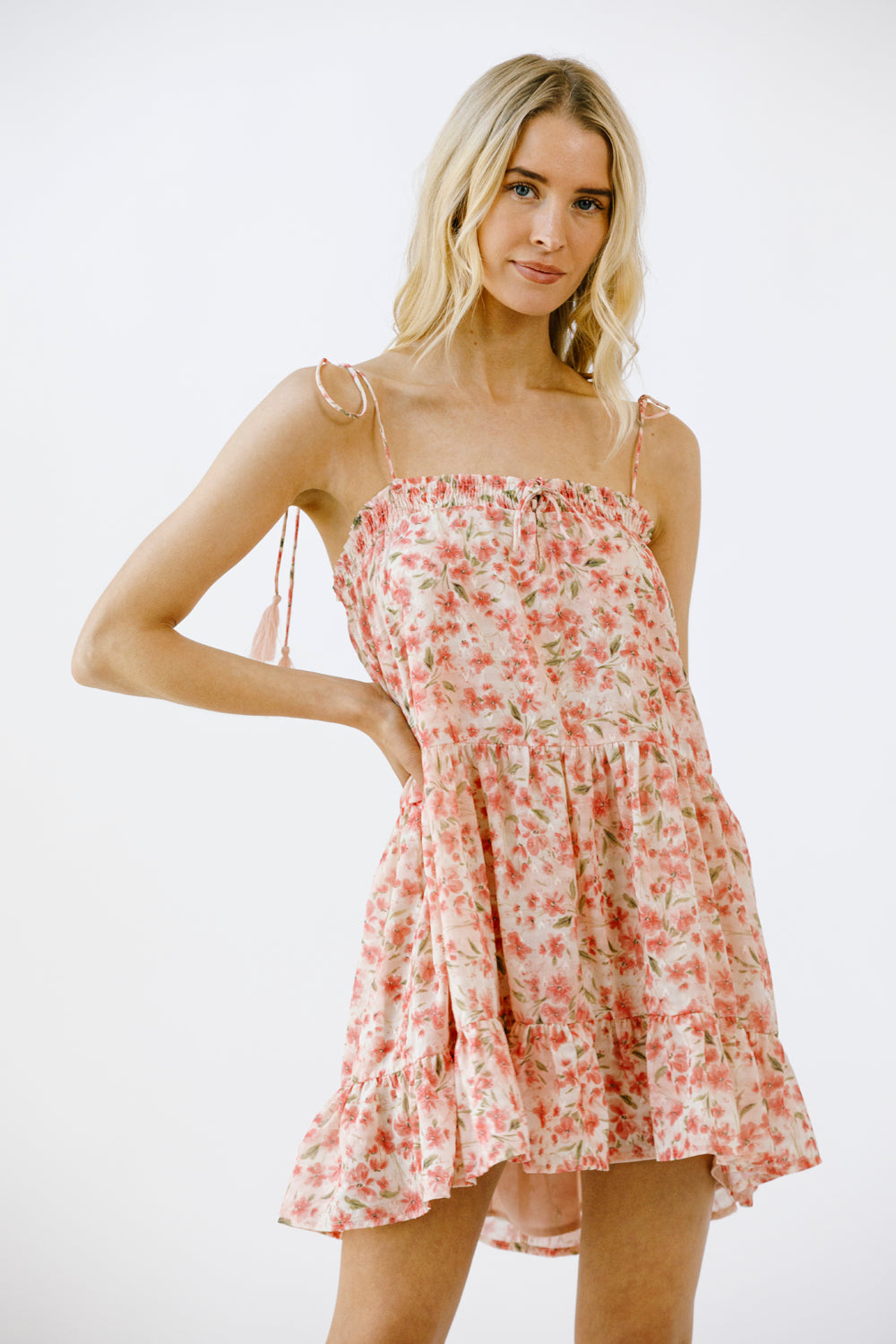 Woman wearing a vibrant pink floral print mini dress on a white background
