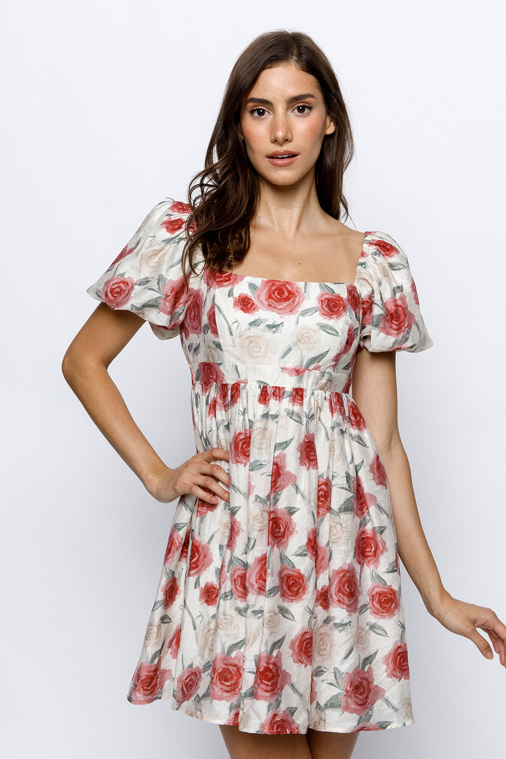 Woman wearing an ivory dress with red roses pattern on a white background