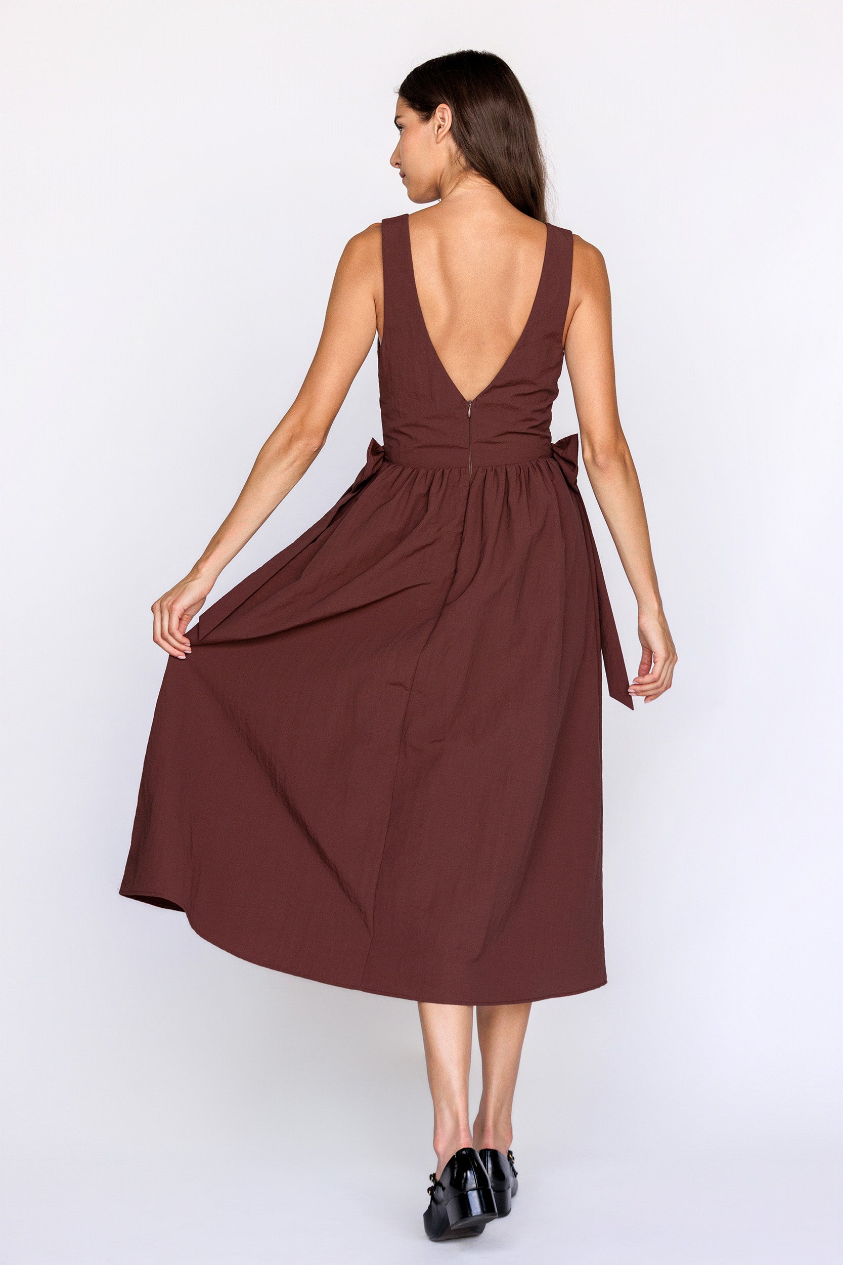 Woman wearing a brown dress with an open back on a white background
