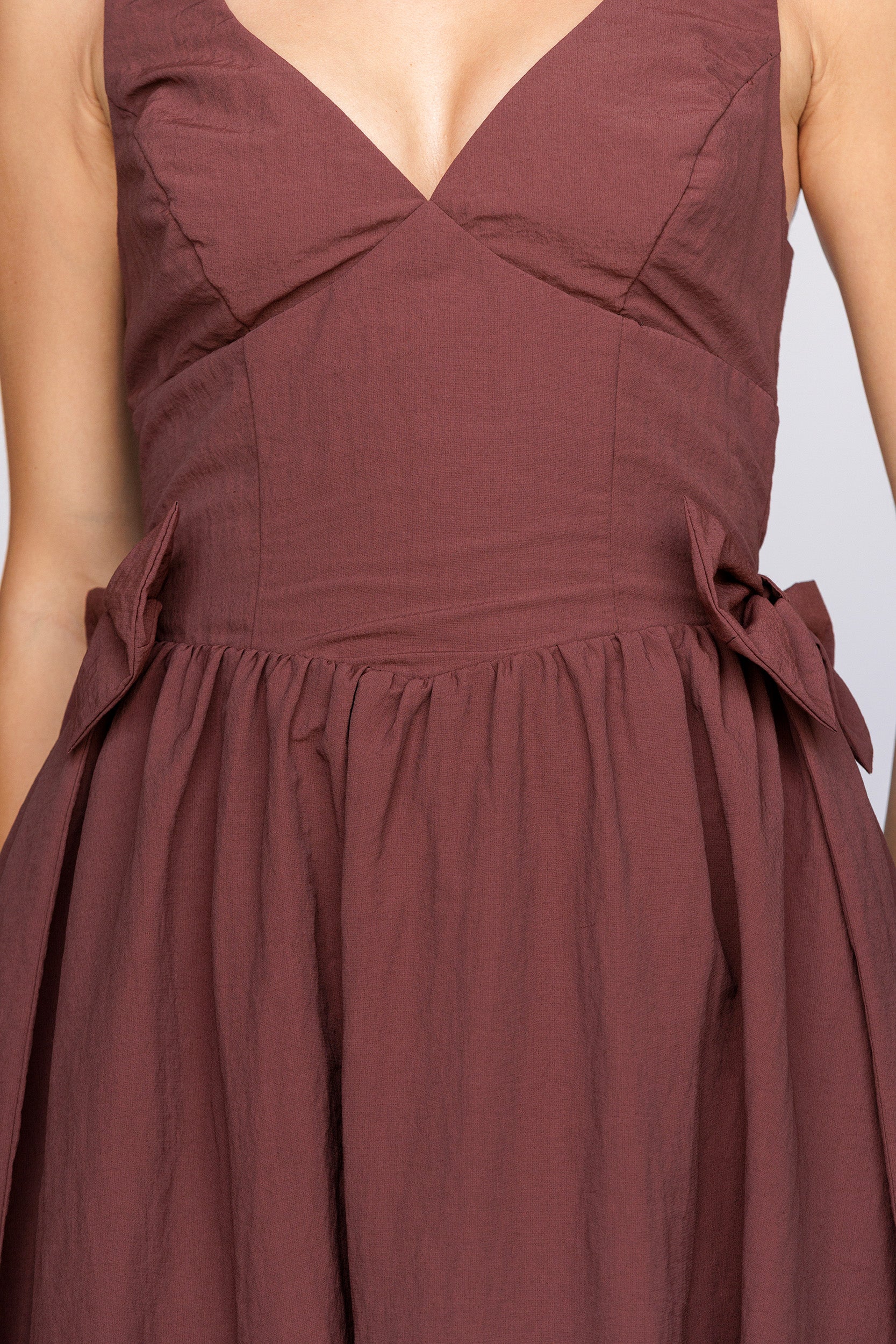 Brown dress with bow details on a plain background