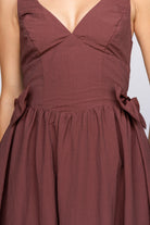 Brown dress with bow details on a plain background