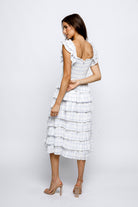 Woman wearing a white checkered dress with ruffled sleeves on a white background.