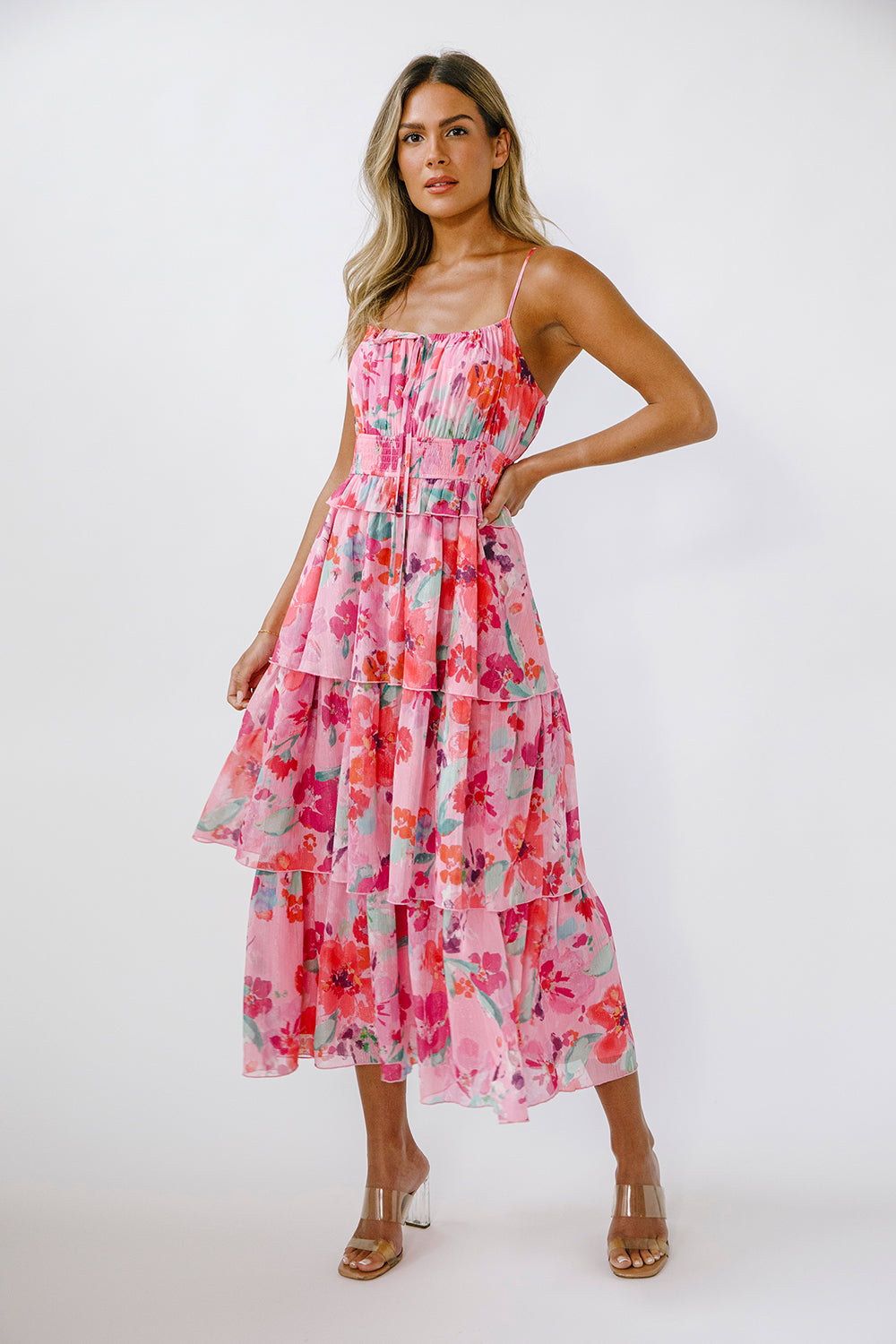 Woman wearing a vibrant pink floral dress on a white background