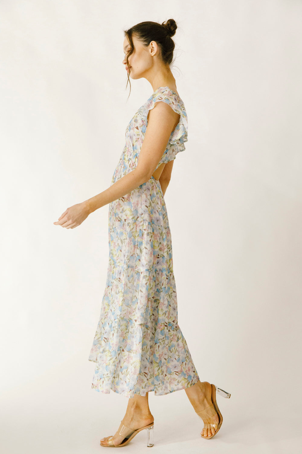 Side view of a woman wearing a blue and pink floral dress on a white background