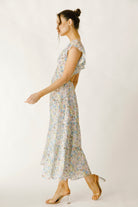 Side view of a woman wearing a blue and pink floral dress on a white background