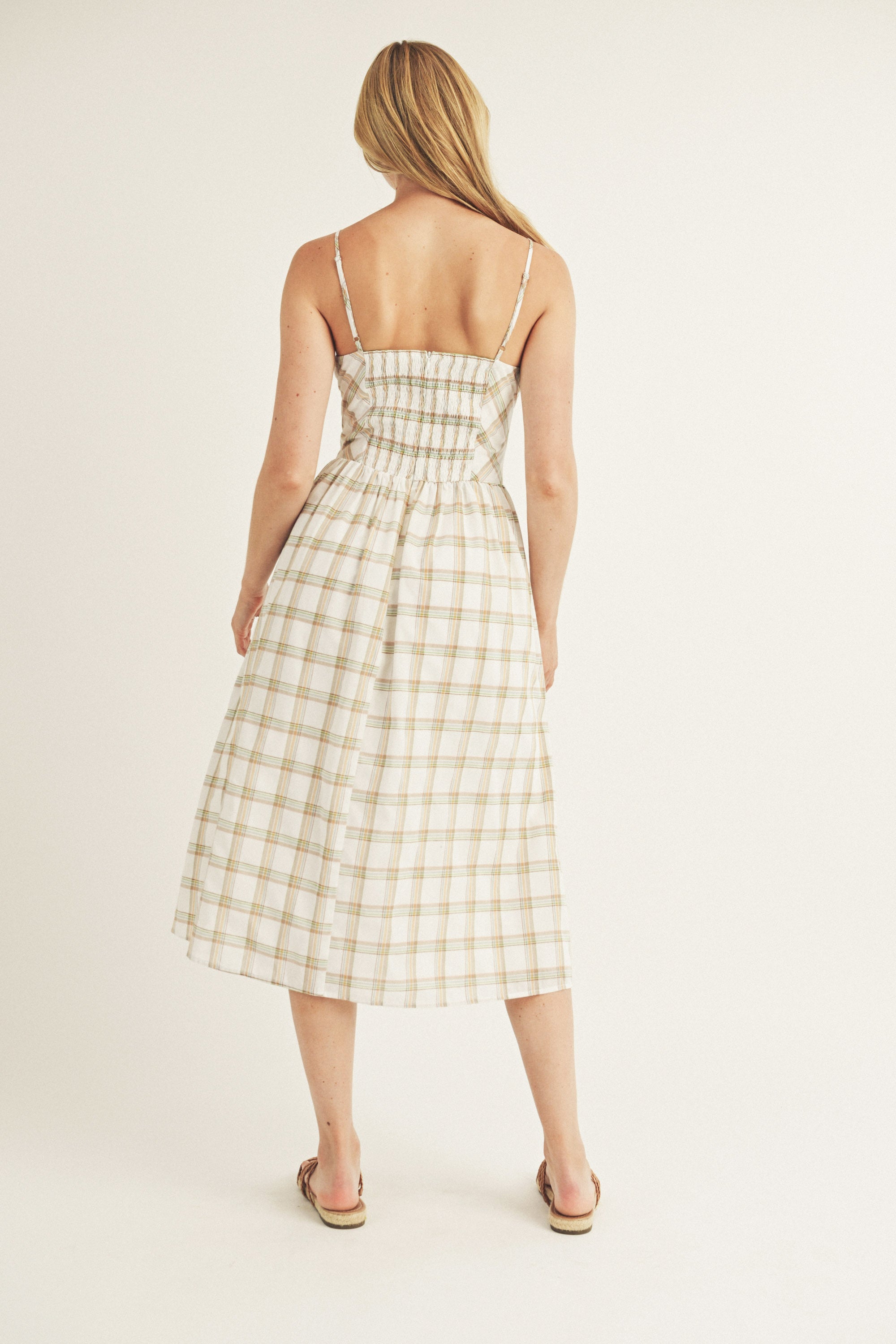 Back view of a woman wearing a mint plaid dress from behind on a plain background