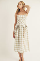 Woman wearing a mint plaid dress on a plain background
