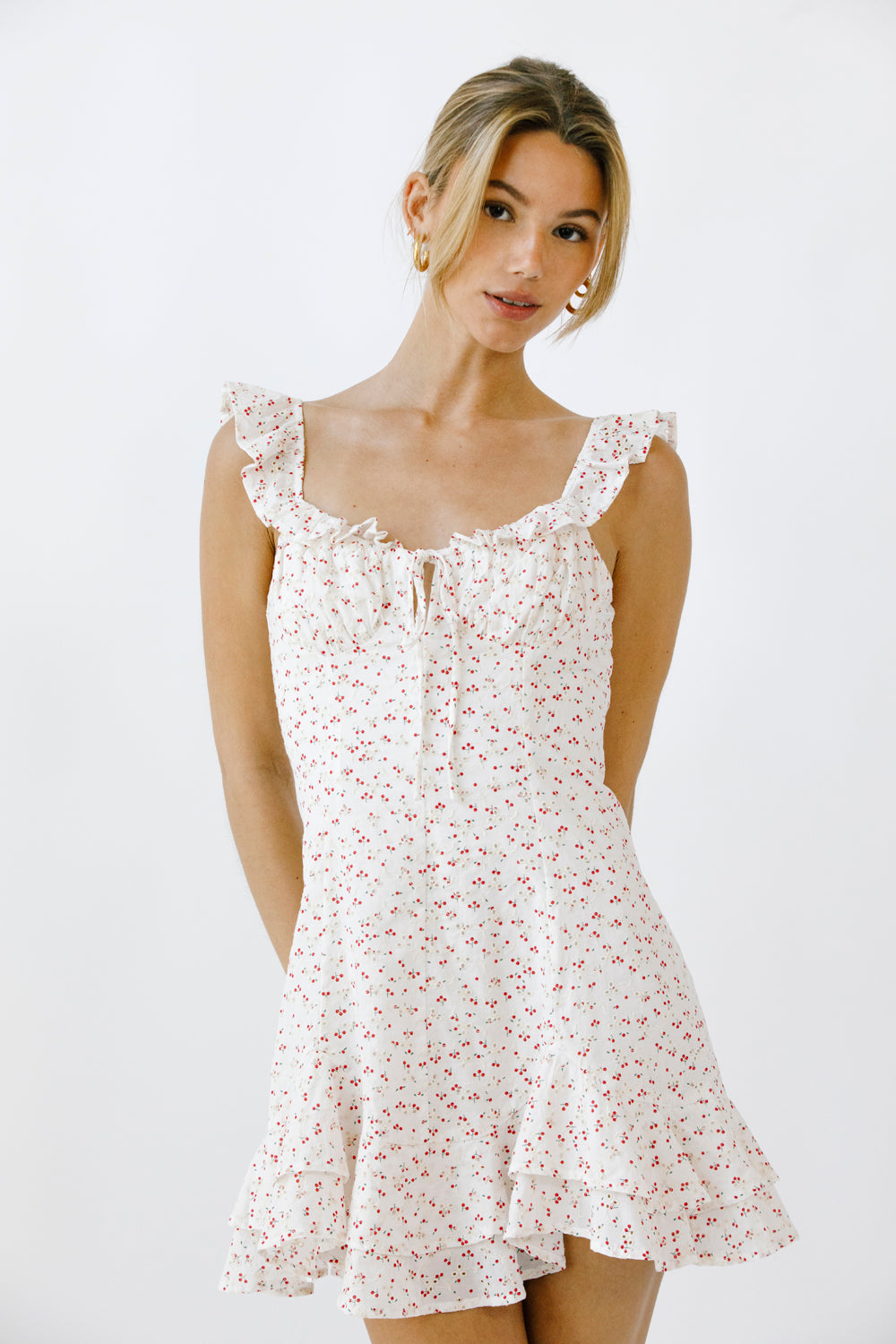 Woman wearing a white and red floral dress against a plain background