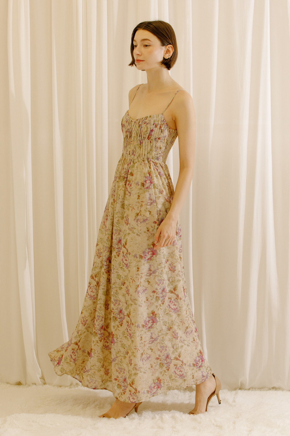 Side view of a model wearing a maxi dress with a romantic floral print and a flowy maxi silhouette.