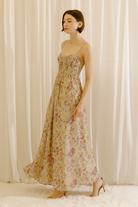 Side view of a model wearing a maxi dress with a romantic floral print and a flowy maxi silhouette.