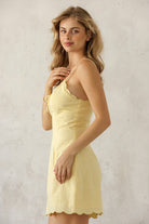 Woman wearing a yellow dress against a plain background