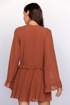 Brown dress with long sleeves and ruffled layers on a white background