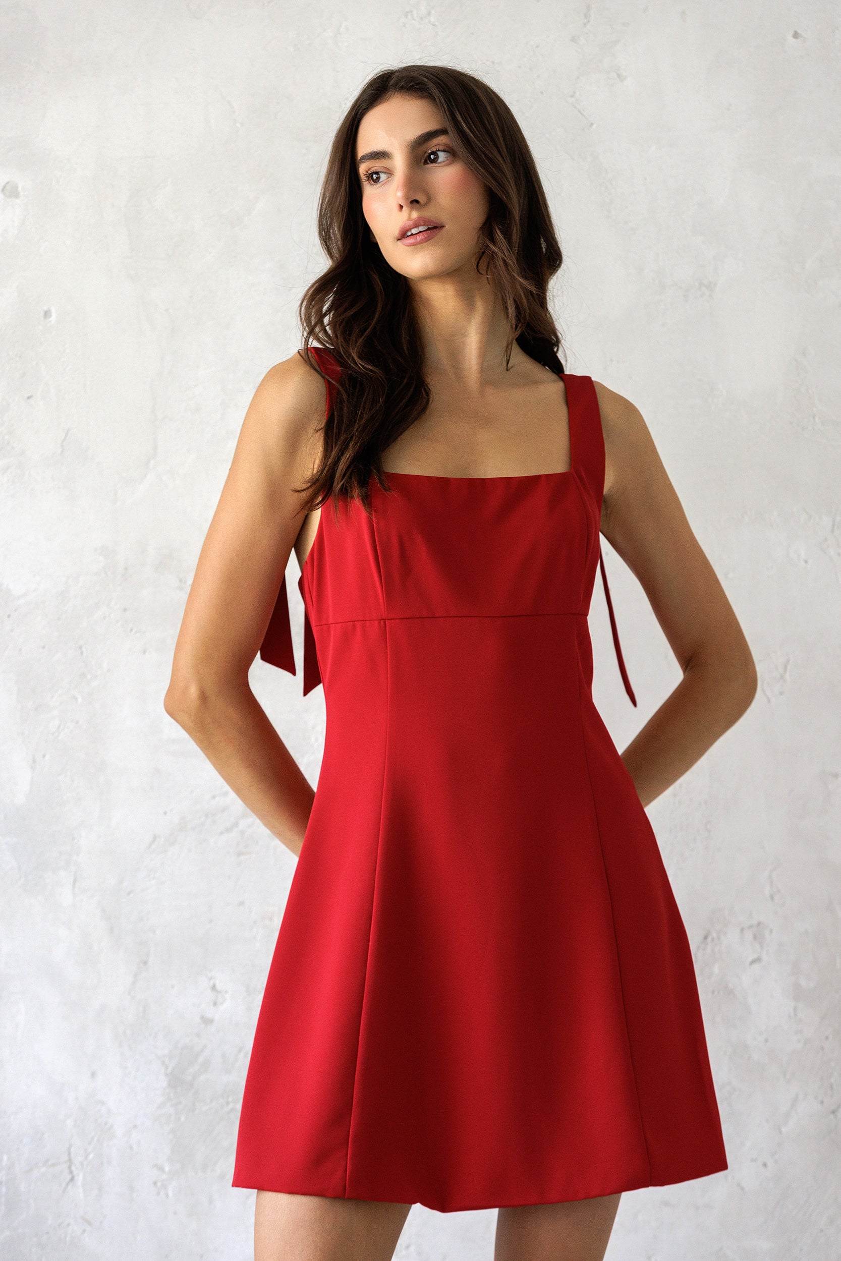 A model wearing a vibrant cherry red mini dress with a square neckline, and flattering fit-and-flare silhouette for effortless day-to-night style.