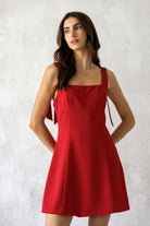 A model wearing a vibrant cherry red mini dress with a square neckline, and flattering fit-and-flare silhouette for effortless day-to-night style.