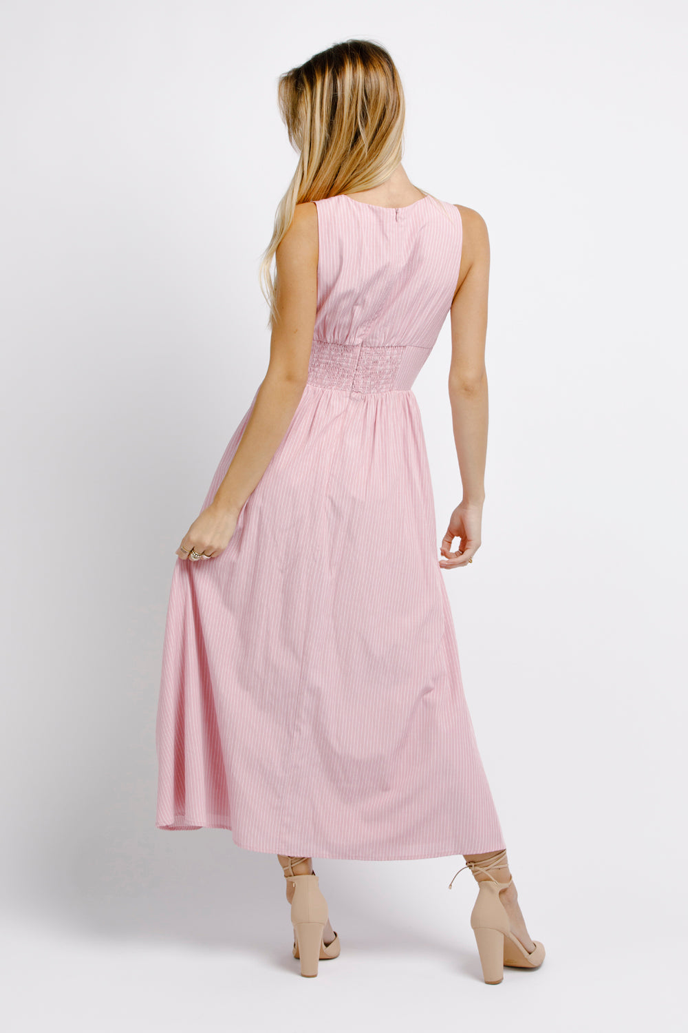 Back view of a woman wearing a pink midi dress on a white background