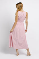 Back view of a woman wearing a pink midi dress on a white background