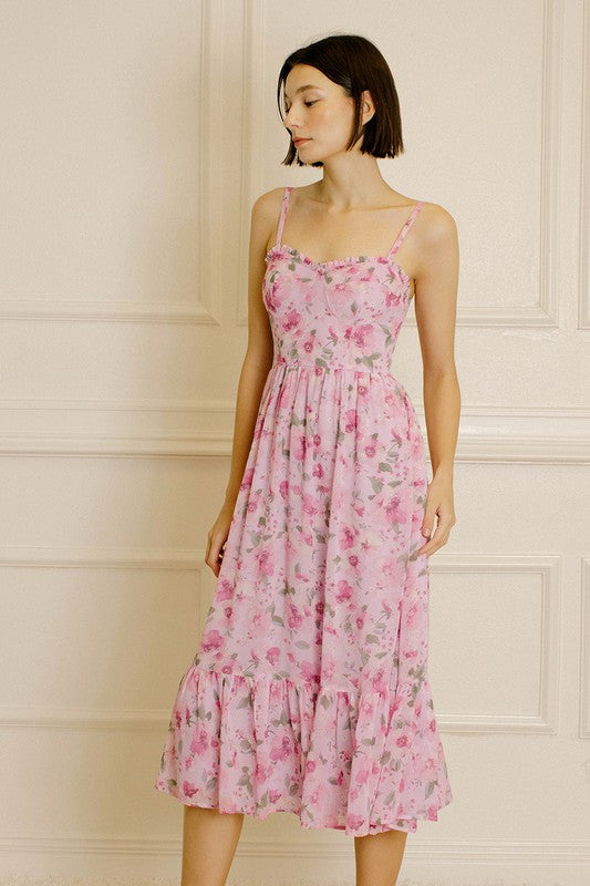 Woman wearing a pink floral dress against a neutral wall.