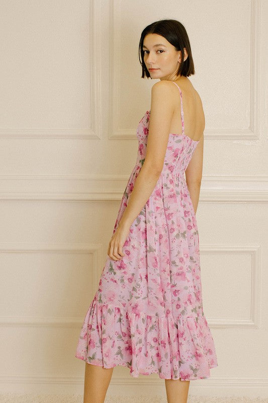 Back view of a woman wearing a pink floral dress against a neutral wall.