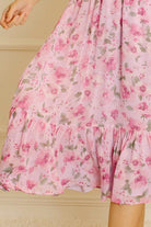 Pink floral dress against a neutral wall.