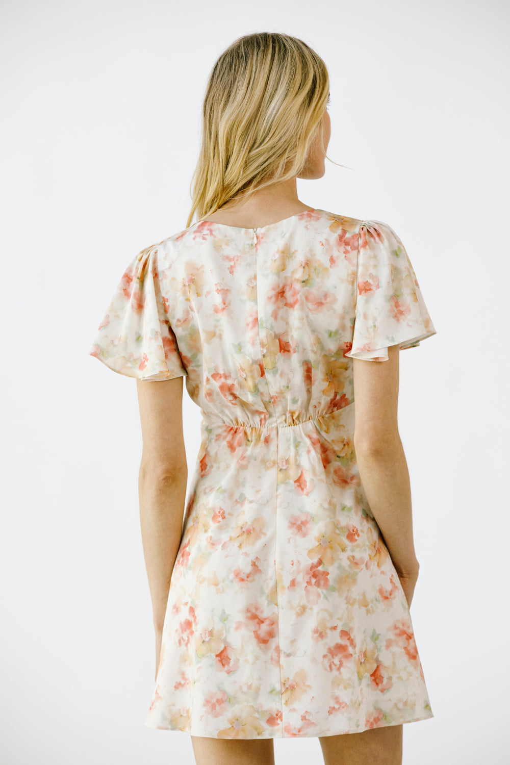 Back view of a woman wearing a floral dress on a white background