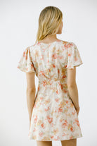 Back view of a woman wearing a floral dress on a white background