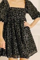Black dress with star pattern worn by a person against a neutral background