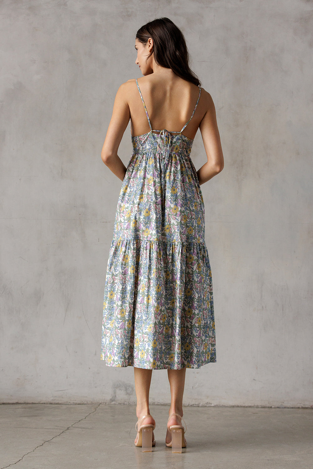 Woman wearing a floral dress and brown high-heels with a neutral background