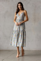 A woman wearing a floral midi dress with a fitted bodice, deep V-neckline, and adjustable spaghetti straps.