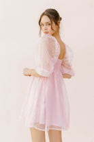 Woman wearing a light pink sequin dress against a white background
