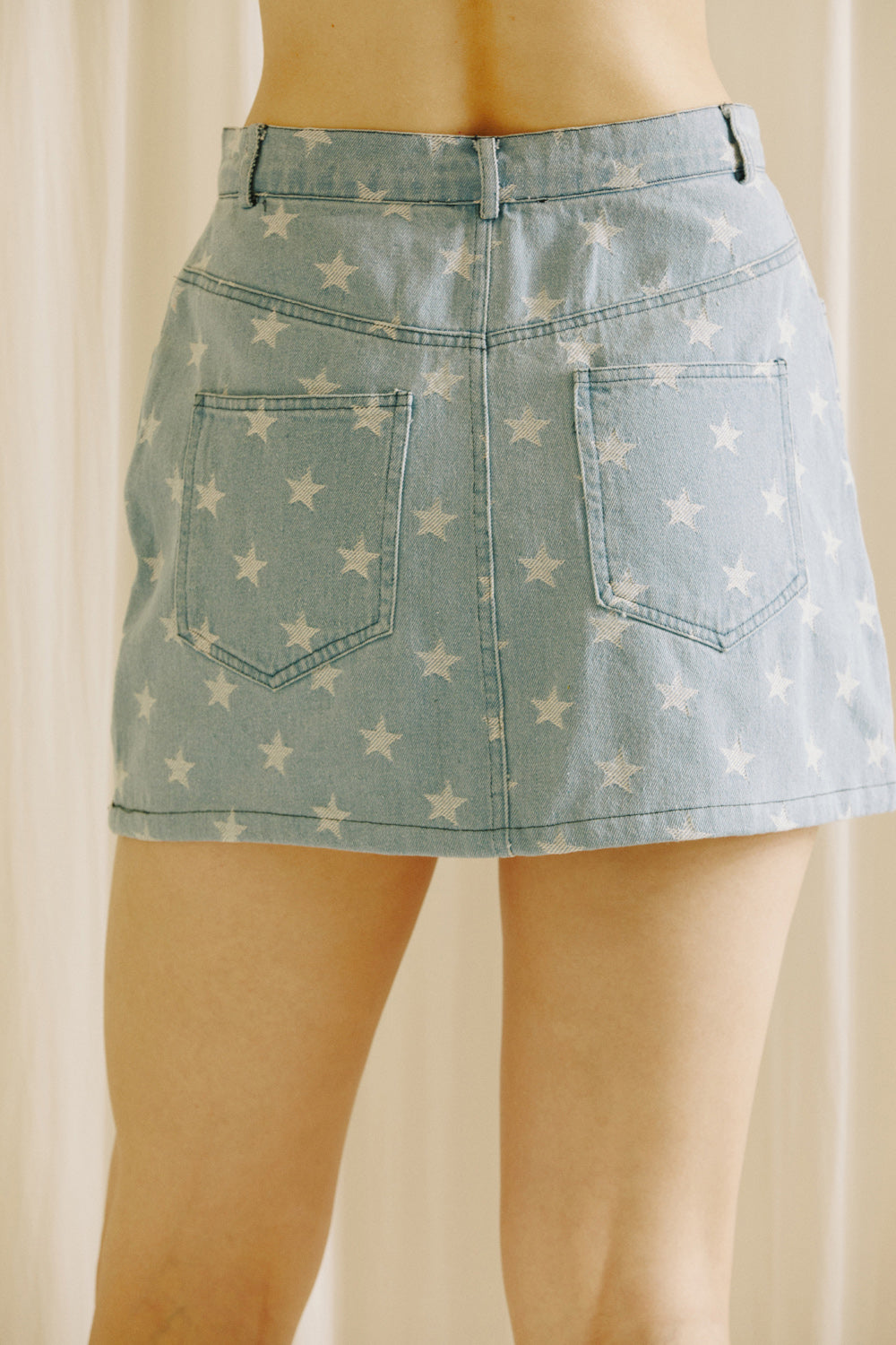 Back view of a model wearing a star-patterned denim skirt  against a neutral background