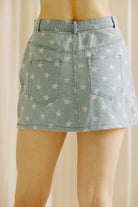 Back view of a model wearing a star-patterned denim skirt  against a neutral background