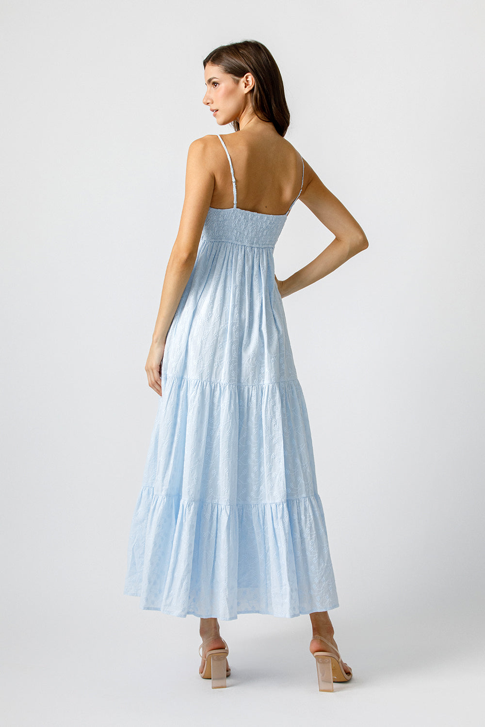 Back view of a woman wearing a light blue dress on a white background
