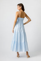 Back view of a woman wearing a light blue dress on a white background