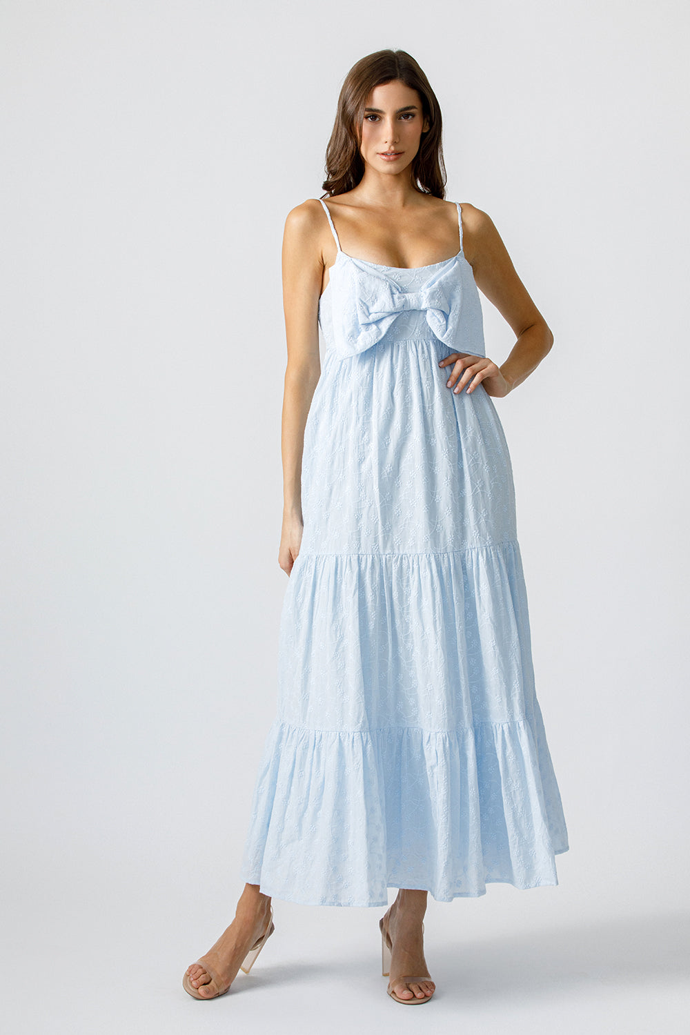 Woman wearing a light blue dress with a bow detail on a white background