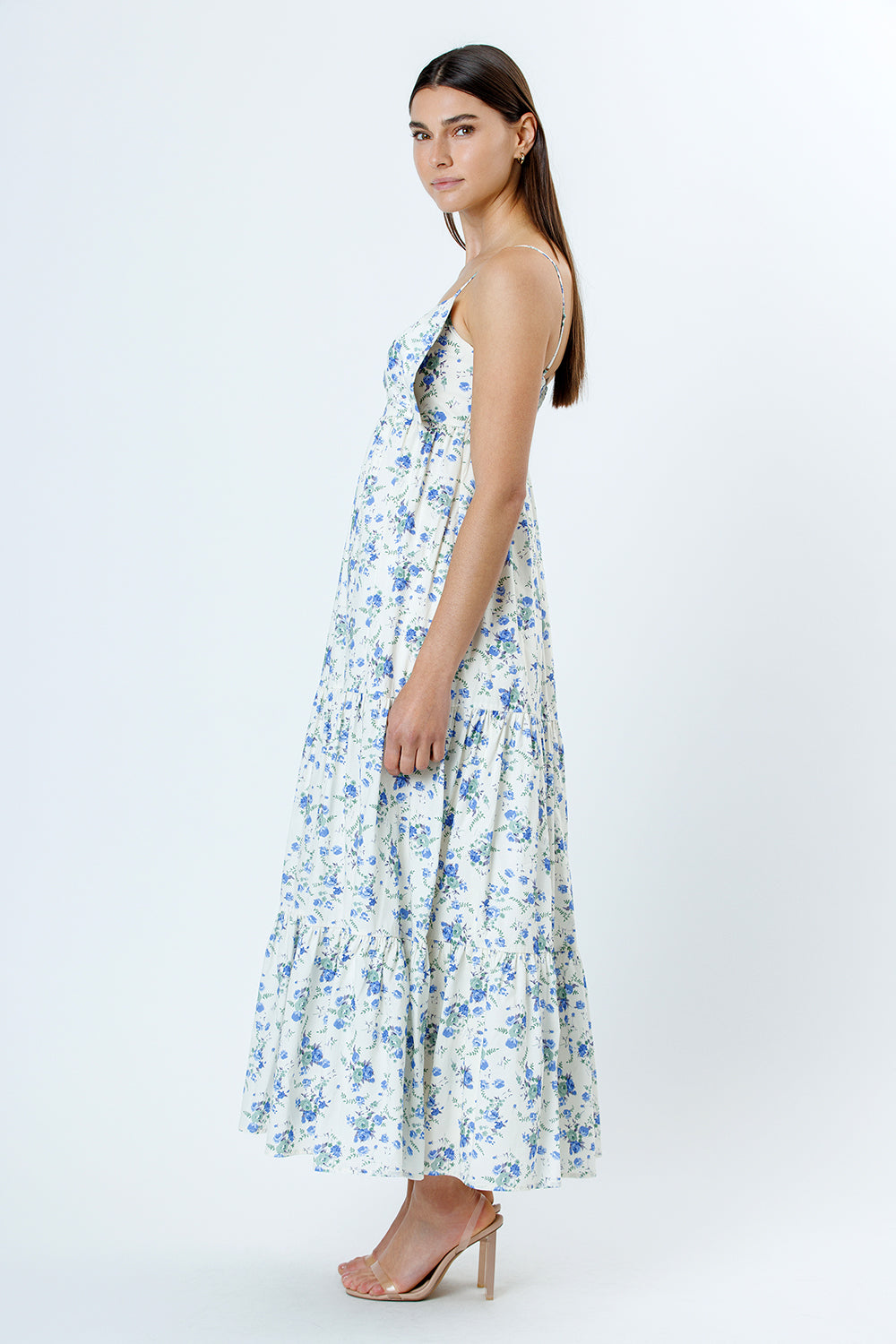 Side view of a woman wearing a floral dress with blue flowers on a white background