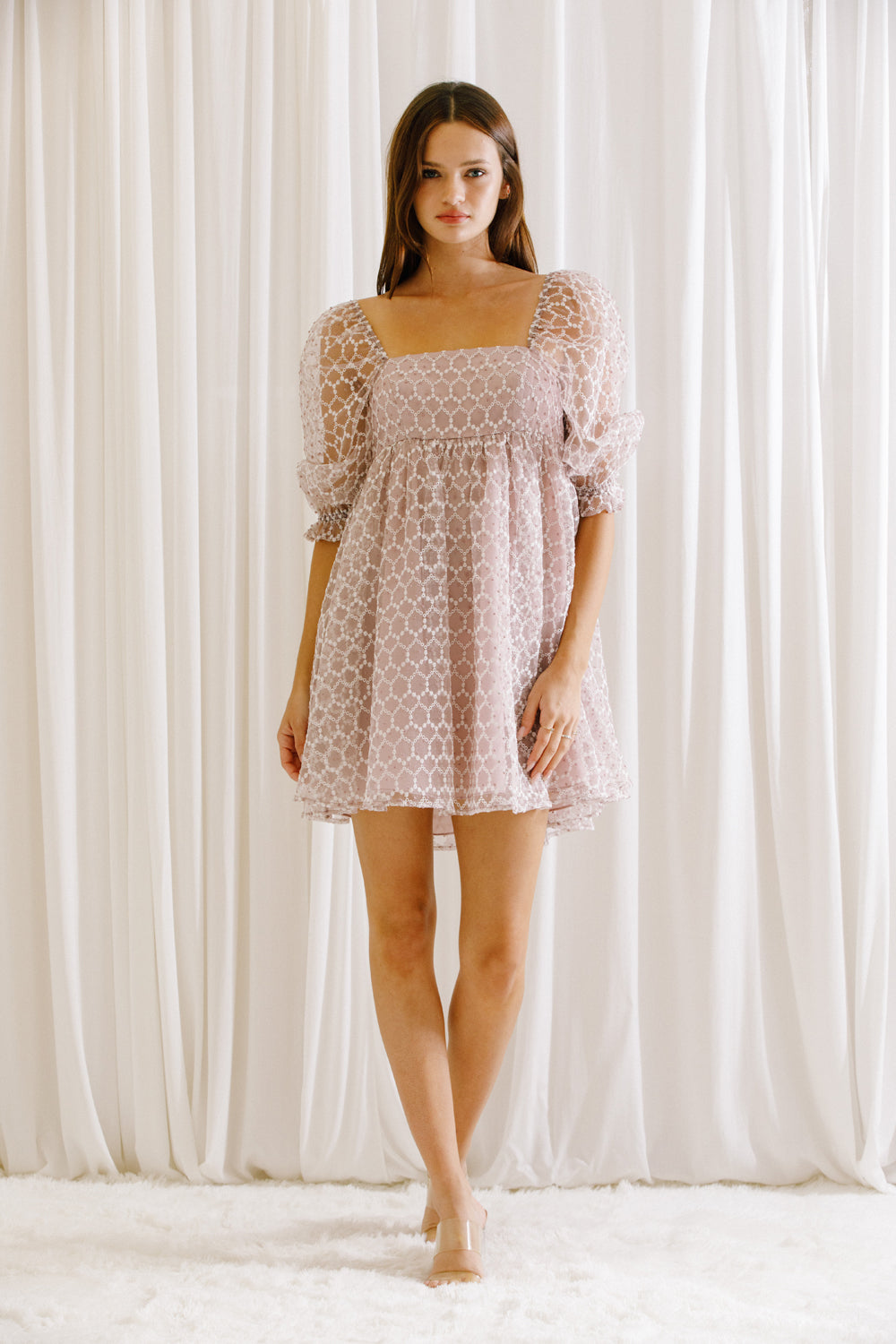 Model wearing a lilac mini dress with mini daisies embroidery and puffy sleeves